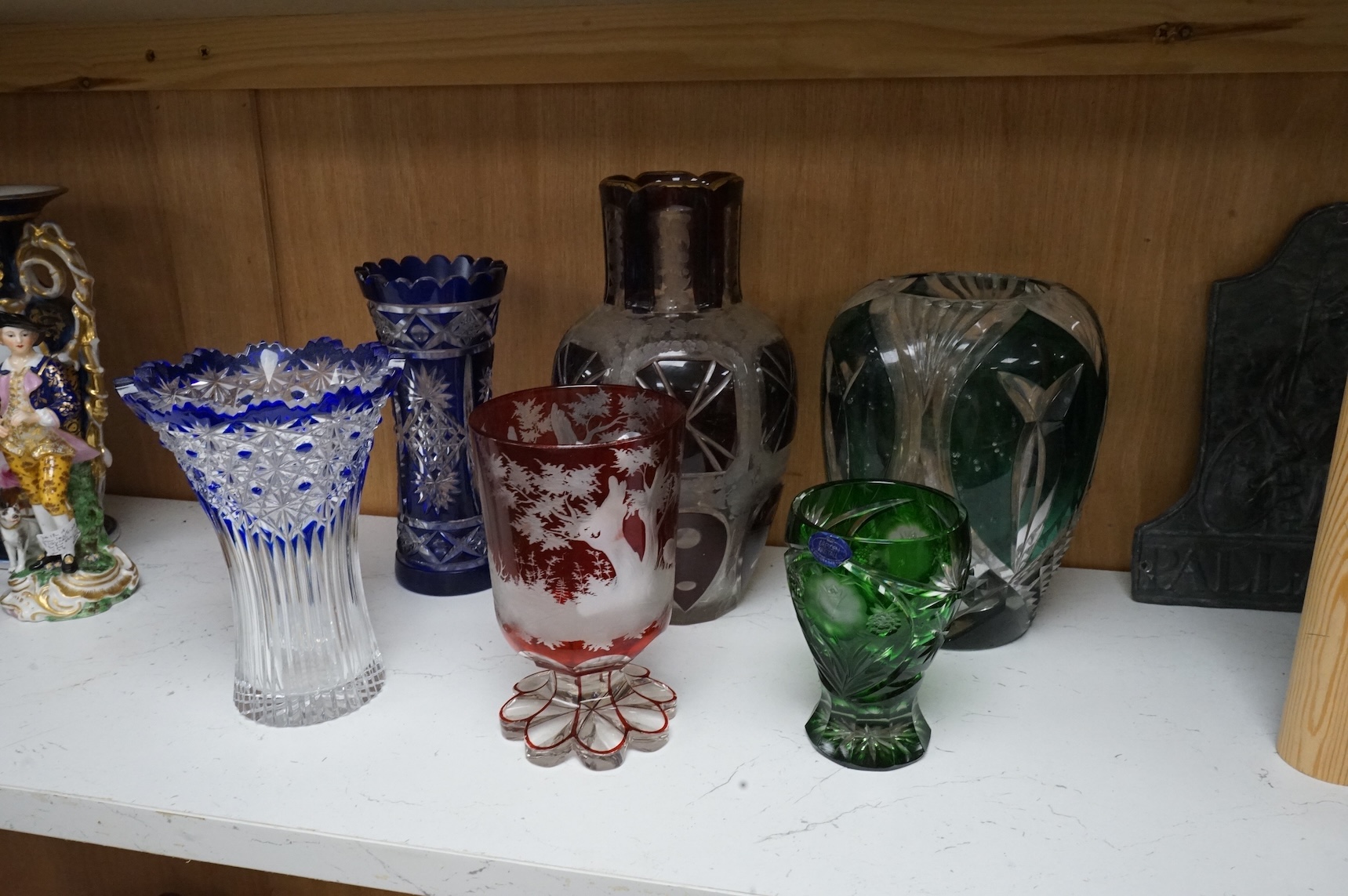 A Bohemian cut and etched red overlay glass goblet decorated with deer in a forest, and other coloured glassware, largest 25cm high